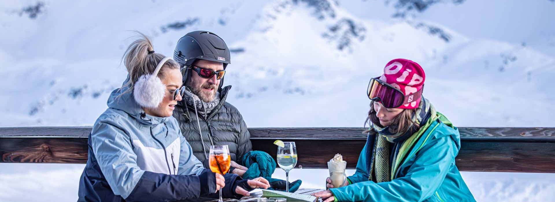 3 Personen sitzen auf einer Terrasse im Schnee