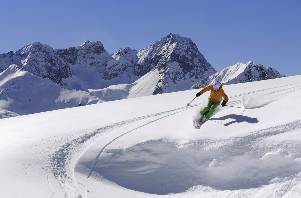 Skifahrer fährt verschneiten Tiefschneehang hinab