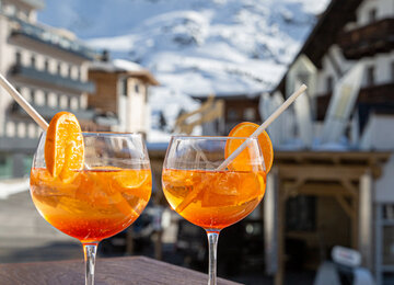 Zwei Gläser Aperol vor Bergpanorama