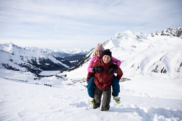 Mann trägt Frau Huckepack durch den Schnee