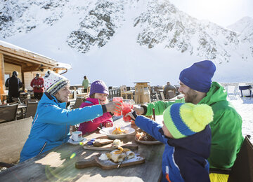 Familie stößt mit Getränken bei gemütlicher Hütteneinkehr an