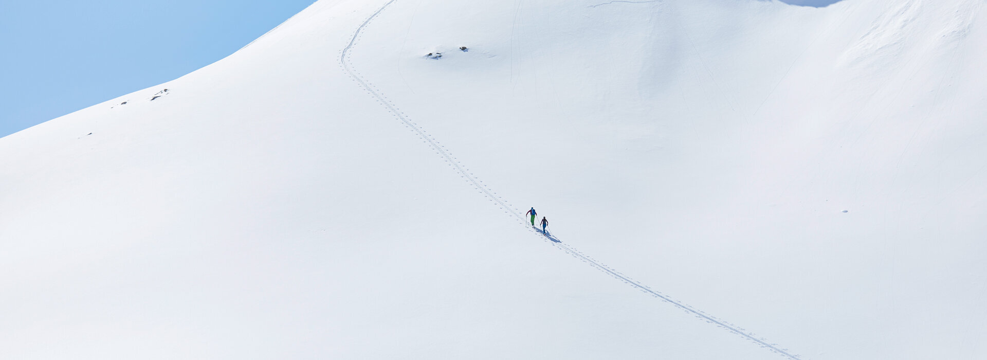 Verschneiter Hang mit 2 Skitourengehern und einer Spur