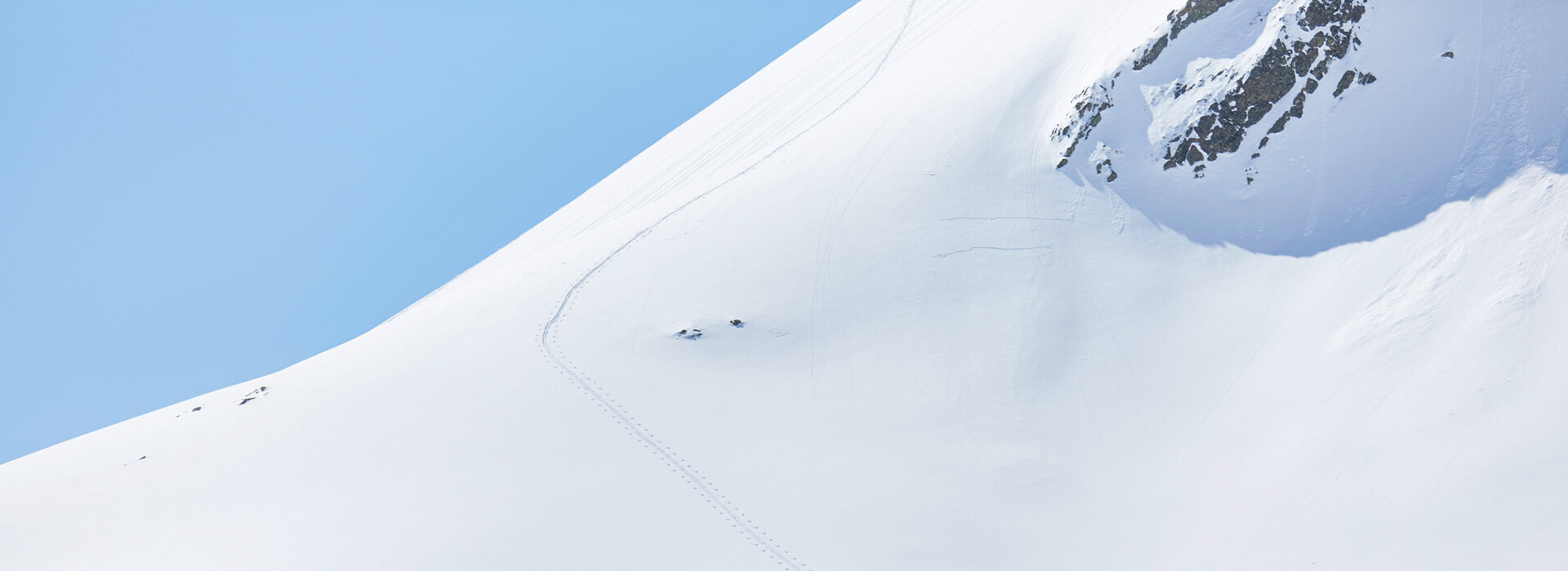 Verschneiter Hang mit 2 Skitourengehern und einer Spur