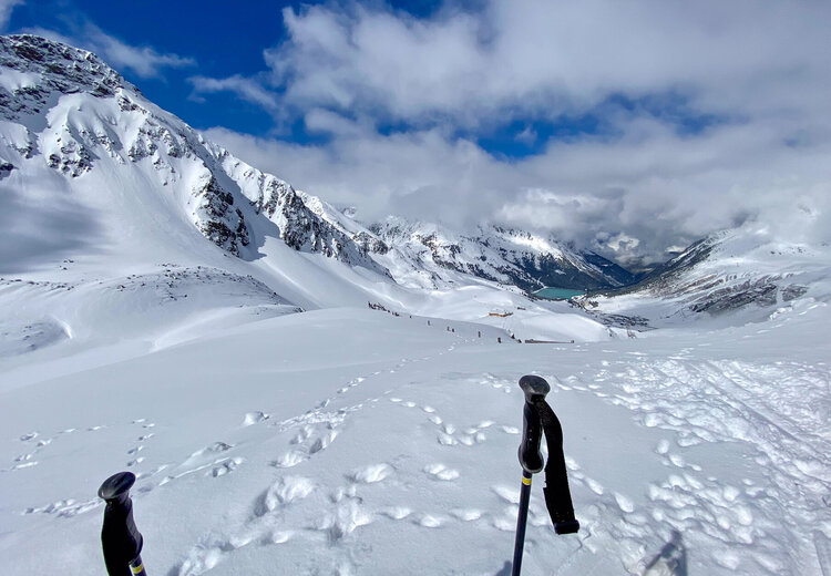 Zwei Skistöcke im Schnee vor Bergpanorama
