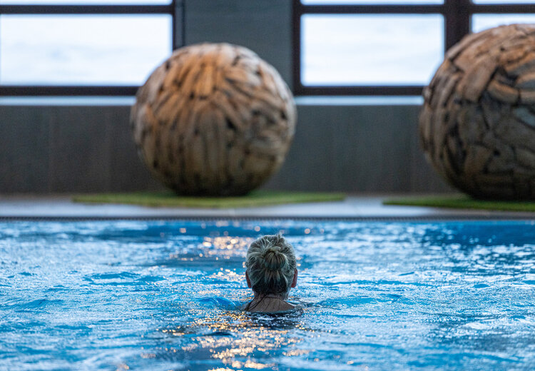 Frau schwimmt im Hallenbad