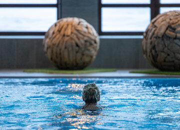 Frau schwimmt im Hallenbad